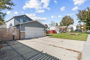 View of side of home featuring a gate, brick siding, and concrete driveway