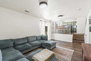 Living room featuring dark wood-style flooring and a textured ceiling