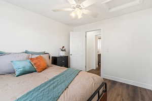 Bedroom with attic access, dark wood-style flooring, and a ceiling fan