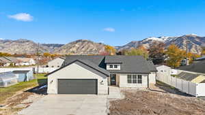View of front of property featuring a mountain view, a garage, a shingled roof, driveway, and stone siding