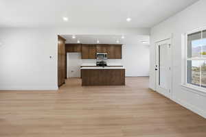 Kitchen with a kitchen island with sink, open floor plan, light countertops, recessed lighting, and light wood-style flooring
