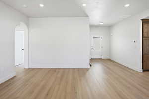 Living room featuring light wood finished floors, recessed lighting, and arched walkways