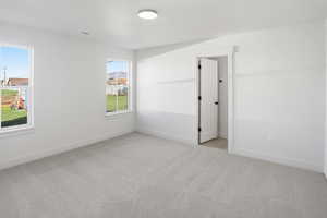 Primary suite with light colored carpet and baseboards