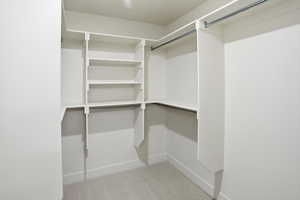 Primary suite walk in spacious closet featuring light carpet