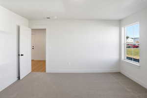 Primary suite featuring light colored carpet and plenty of natural light,
