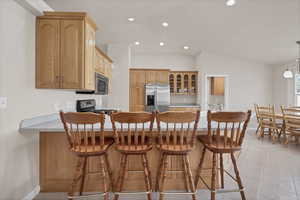 Kitchen featuring recessed lighting, a peninsula, glass insert cabinets, a breakfast bar, and pendant lighting