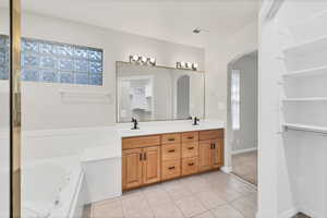 Bathroom with double vanity, a tub with jets, and light tile patterned flooring