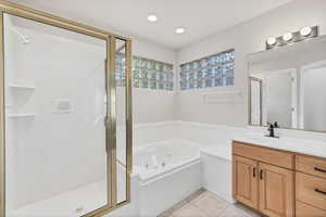 Bathroom with a jetted tub, vanity, light tile patterned floors, a shower stall, and recessed lighting