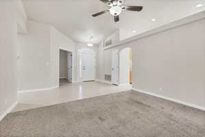 Empty room featuring light tile patterned floors, light carpet, a ceiling fan, recessed lighting, and arched walkways