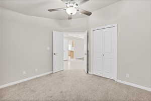 Unfurnished bedroom featuring light carpet, a closet, ceiling fan, and arched walkways