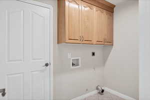 Laundry room with hookup for a gas dryer, washer hookup, cabinet space, light tile patterned floors, and hookup for an electric dryer