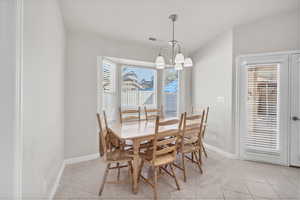Dining area with light tile patterned floors, a chandelier, and vaulted ceiling