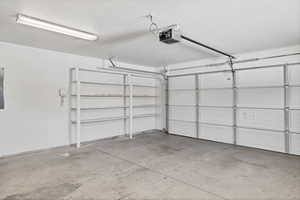Garage featuring a garage door opener and baseboards