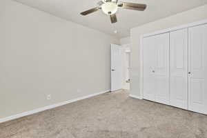 Unfurnished bedroom with carpet floors, a closet, and a ceiling fan