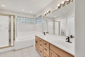 Full bath featuring a shower stall, double vanity, light tile patterned flooring, a garden tub, and recessed lighting
