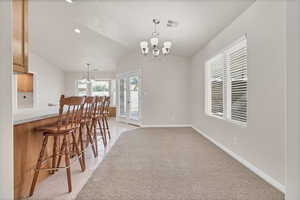 Dining room featuring a chandelier, light tile patterned flooring, vaulted ceiling, and recessed lighting