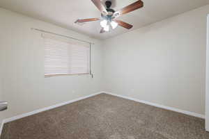 Carpeted spare room with baseboards and a ceiling fan