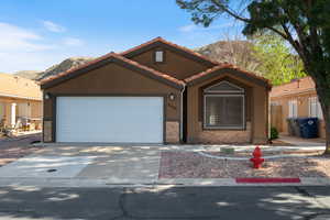 Single story home with a mountain view, driveway, a tile roof, stucco siding, and an attached garage