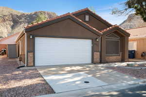 View of front of house with stone siding, driveway, a mountain view, and stucco siding