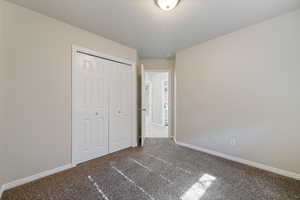 Unfurnished bedroom featuring carpet, a closet, and a textured ceiling