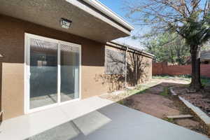 View of side of property featuring a patio area, a fenced backyard, and stucco siding