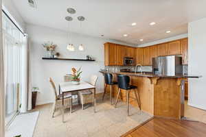 Kitchen featuring brown cabinets, a peninsula, a kitchen breakfast bar, decorative backsplash, and appliances with stainless steel finishes