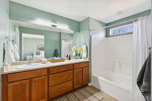 Ensuite bathroom featuring light tile patterned floors, shower / tub combo with curtain, and double vanity