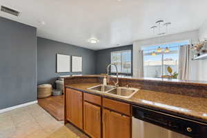 Kitchen with dishwasher, hanging light fixtures, brown cabinets, and light tile patterned flooring