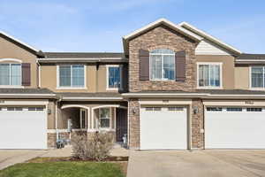View of front of property with stone siding, a garage, covered porch, concrete driveway, and stucco siding