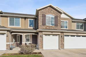Craftsman inspired home featuring stone siding, stucco siding, and a garage