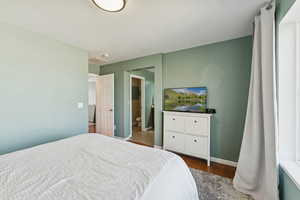 Bedroom with dark wood finished floors, a textured ceiling, and ensuite bath