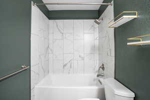 Bathroom featuring a textured wall and washtub / shower combination