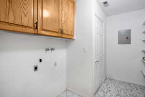 Laundry room featuring light marble finish flooring, electric panel, hookup for a washing machine, cabinet space, and electric dryer hookup