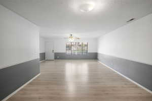 Unfurnished room with light wood-style floors, a textured ceiling, a ceiling fan, and a textured wall