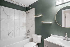 Bathroom featuring a textured wall, shower / bathtub combination, and vanity
