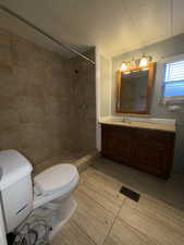Full bathroom featuring vanity, a textured ceiling, a stall shower, and a textured wall