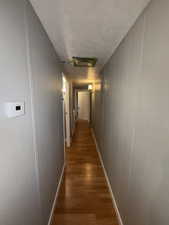 Corridor with dark wood-style flooring, a textured ceiling, and cooling unit