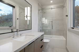 Full bath featuring healthy amount of natural light, vanity, and shower / bath combination with glass door