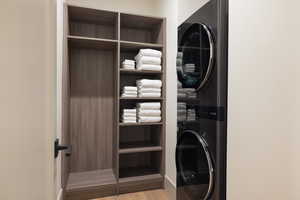 Laundry area with stacked washer / dryer and light wood-style flooring