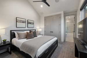 Carpeted bedroom featuring vaulted ceiling, a closet, ensuite bath, ceiling fan, and recessed lighting