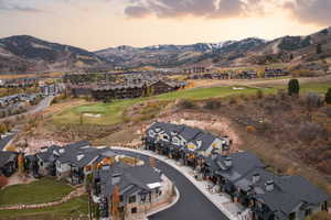 Aerial overview of property's location featuring a golf club, nearby suburban area, and a mountainous background