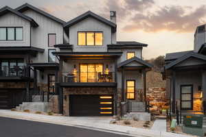 View of front of house with board and batten siding, stone siding, a chimney, and a balcony