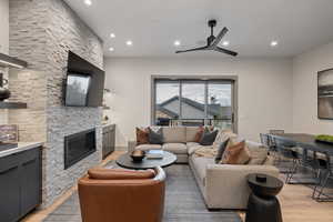 Living room with light wood-style floors, recessed lighting, a fireplace, and ceiling fan