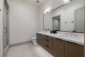 Full bathroom with double vanity, a shower stall, and light tile patterned flooring