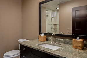 Full bath featuring vanity, a shower stall, and a textured wall