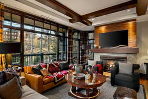 Living area featuring a lit fireplace, beam ceiling, and coffered ceiling