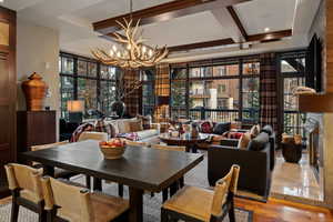 Dining space with a wall of windows, wood finished floors, beam ceiling, and a chandelier