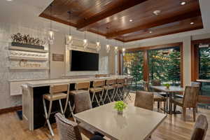 Dining room featuring light wood-style flooring, a wooden ceiling with exposed beams, plenty of natural light, a raised ceiling, and recessed lighting