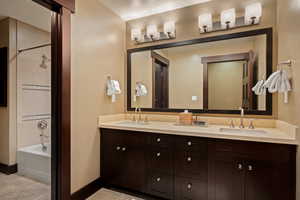 Bathroom with double vanity, light tile patterned floors, and  shower combination