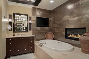Full bath with vanity, a garden tub, tile walls, a fireplace, and recessed lighting